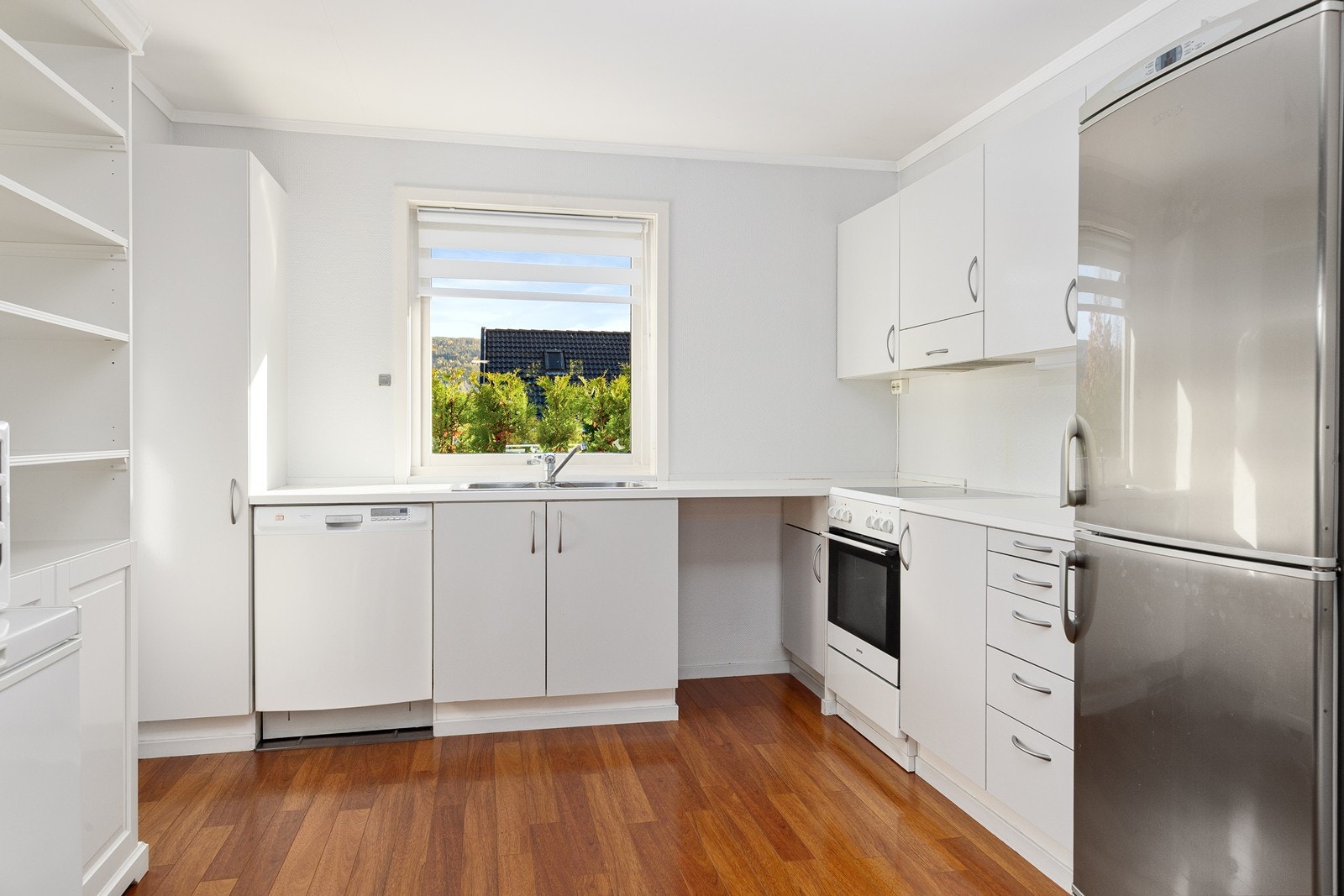 Kjøkkeninnredning med slette malte/laminat fronter i tre/trefiber. Laminat benkeplater og nedfelt stål oppvaskkum/beslag. Galleribilde