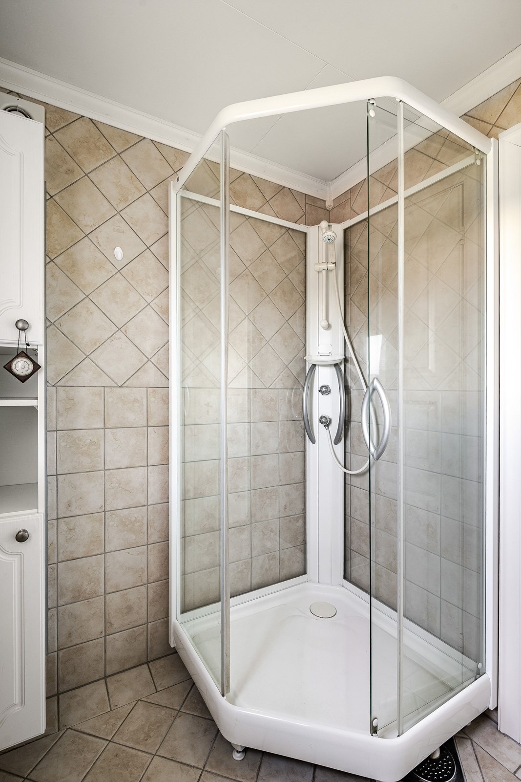 Baderommet er også utstyrt med ekstra høyskap, dusjkabinett og gulvstående toalett. Baderommet har fliser på gulv og vegger, gulvvarme og elektrisk styrt vifte. Galleribilde