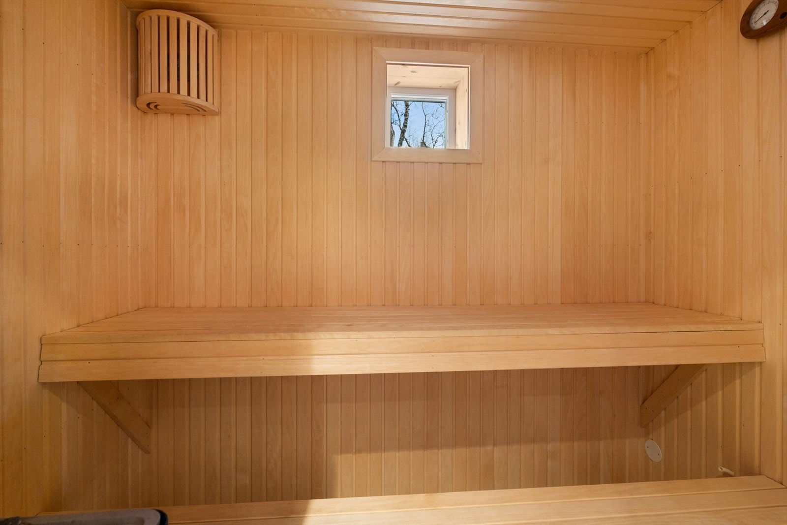 Badstuen har flislagt gulv og panel på vegger og himling, med badstuovn for effektiv oppvarming. Galleribilde