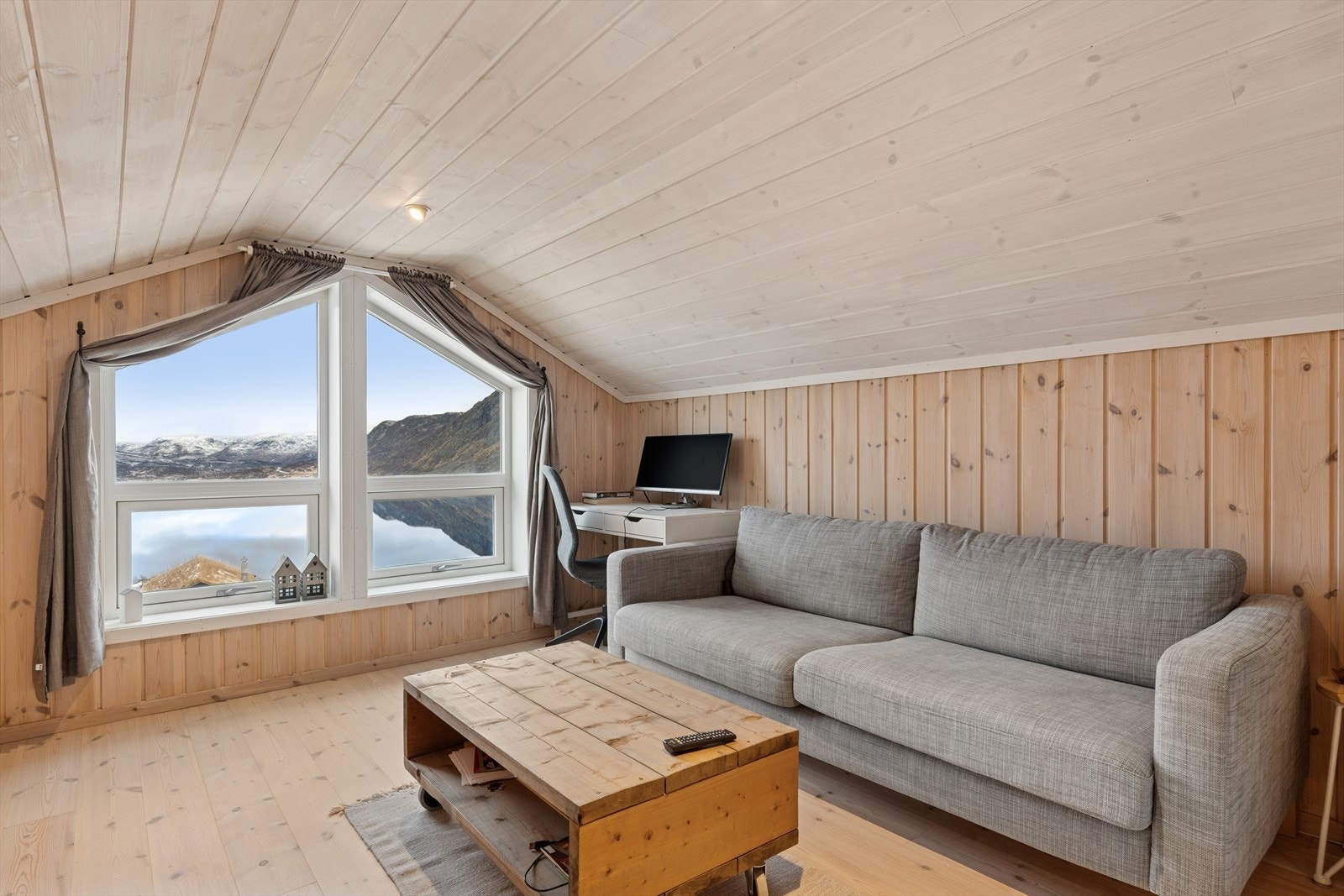 Stor og luftig loftstue med god plass til ønsket møblement. Behandlet furugulv og furupanel på vegger gir en varm og naturlig atmosfære. Store vinduer med energiglass gir utsikt mot fjellandskapet. Galleribilde