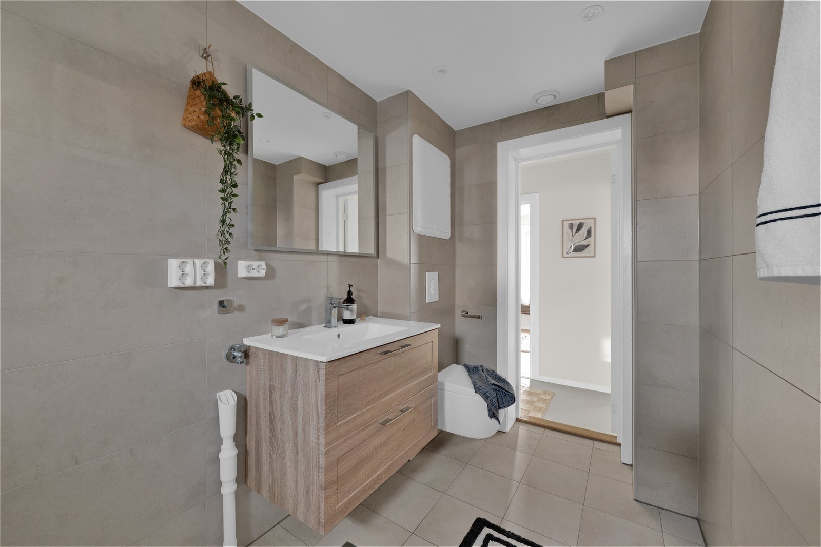 Lekkert baderom med storformat fliser, moderne innredning og opplegg til vaskemaskin. Galleribilde