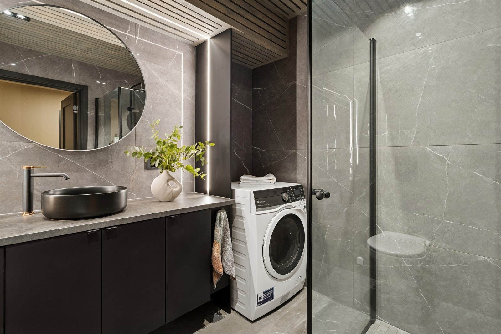 Baderommet er utstyrt med innfellbare dusjvegger av glass og vegghengt toalett. Det er i tillegg opplegg for vaskemaskin. Galleribilde