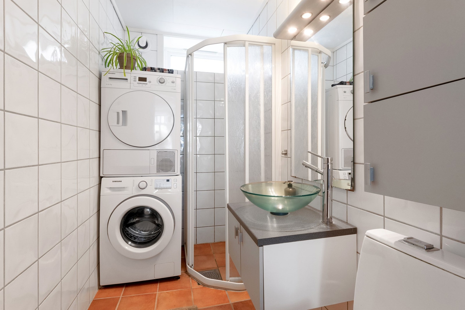 Flislagt bad med dusjkabinett og opplegg for vaskemaskin og tørketrommel Galleribilde