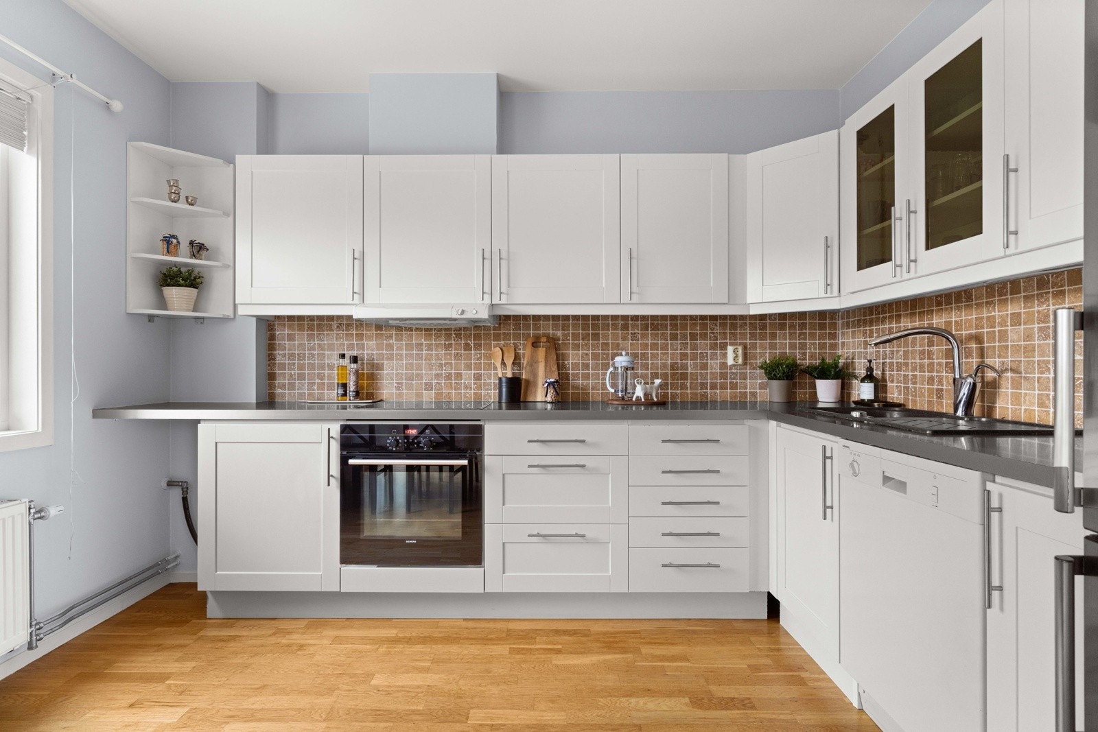 Kjøkkenet har en klassisk og tidløs innredning med hvite, glatte og profilerte fronter og laminert benkeplate Galleribilde