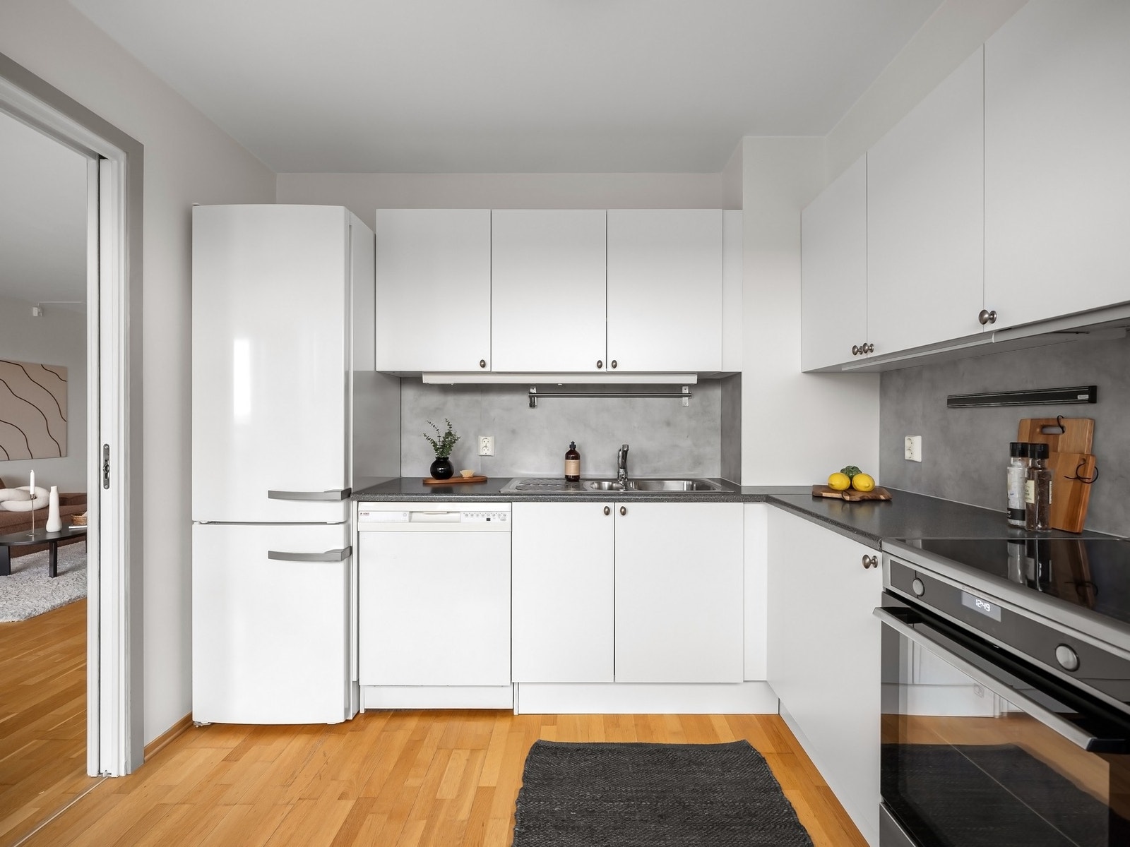 Medfølgende frittstående hvitevarer med oppvaskmaskin, komfyr og kjøl/frys. Stikkontakt på vegg over benk, fliser mellom benk og overskap Galleribilde