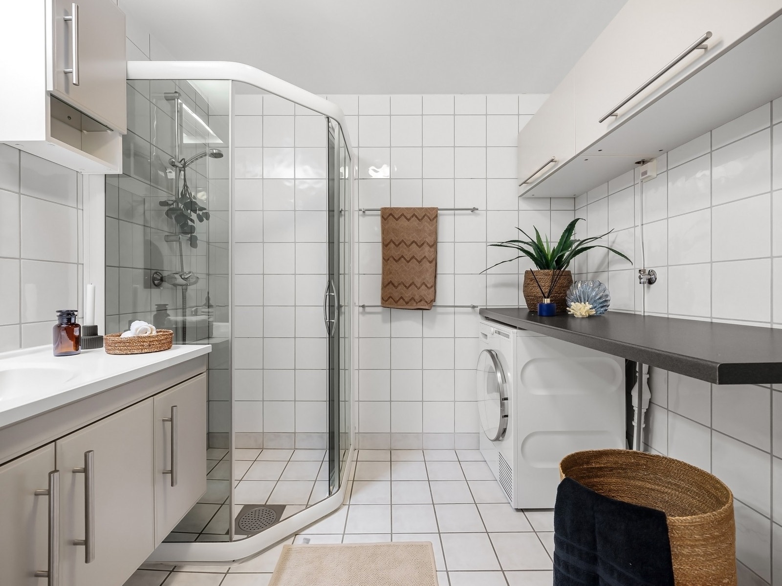 Stilrent baderom fra byggeåret med flislagte vegger i hvit 20x20-format og sokkelfliser som gir en ren og harmonisk helhet Galleribilde