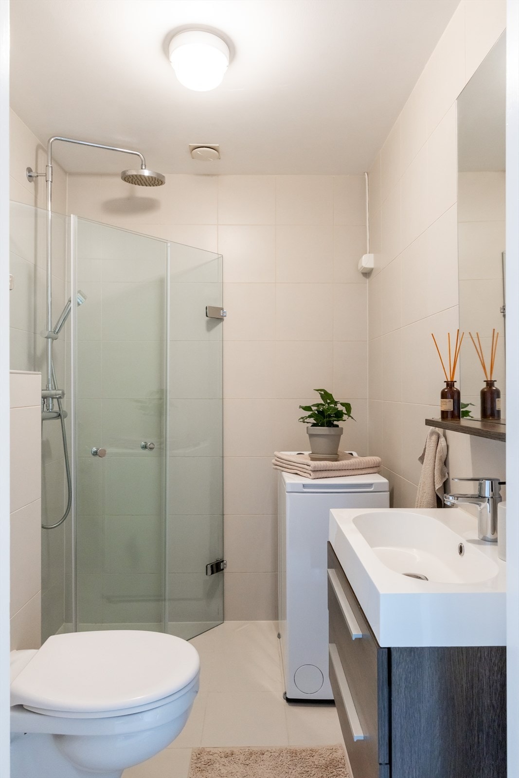 Innredningen består av et stilrent benkeskap med glatte fronter, samt speil og praktisk hylle over servanten. Galleribilde