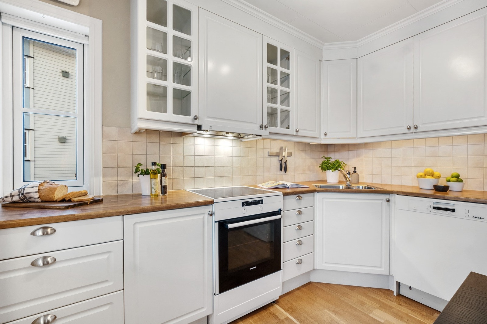 Kjøkkenet har et stilrent og tidløst preg, med hvite, profilerte fronter og en benkeplate i stilen av tre. Galleribilde