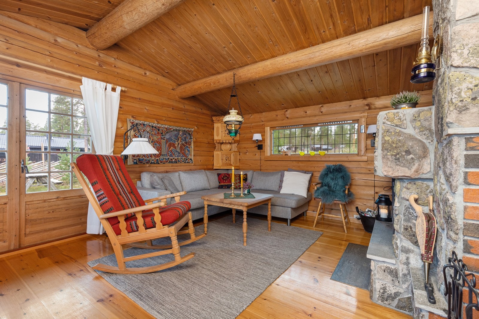 Koselig sofagruppe hvor man kan samles for tv-titting eller brettspill. Terrassedør og lister rundt vinduer er hvitmalte siden bilder ble tatt. Galleribilde