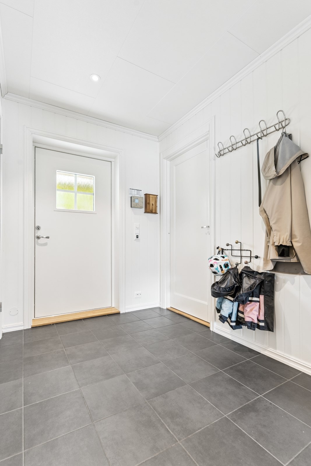 Velkommen inn til ein romsleg gang med flis på golv og malte panelplater på veggar Galleribilde