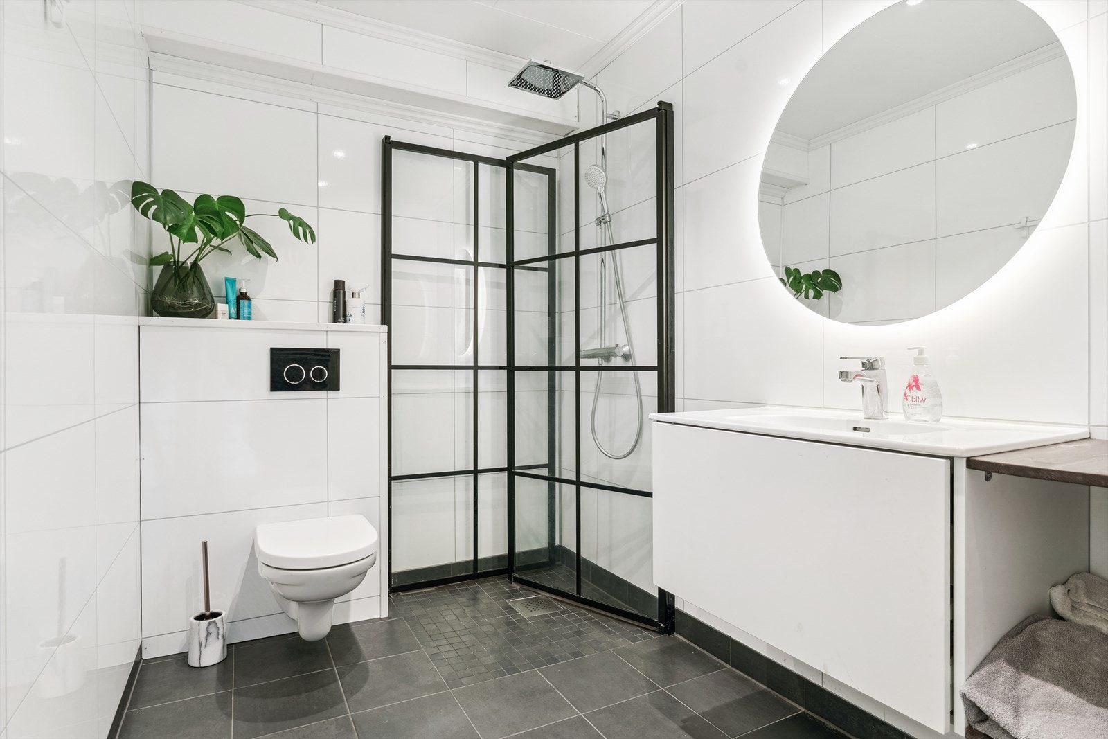 Baderom i 1.etasje med vegghengt toalett, servatinnreiing og dusj på golv med innfellbare dusjdører Galleribilde