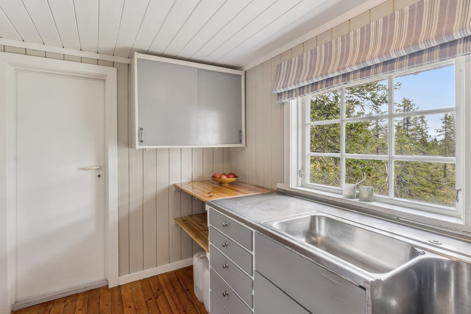 Praktisk kjøkkeninnredning med laminerte hyller og vindu over benken som slipper inn godt med dagslys. Galleribilde