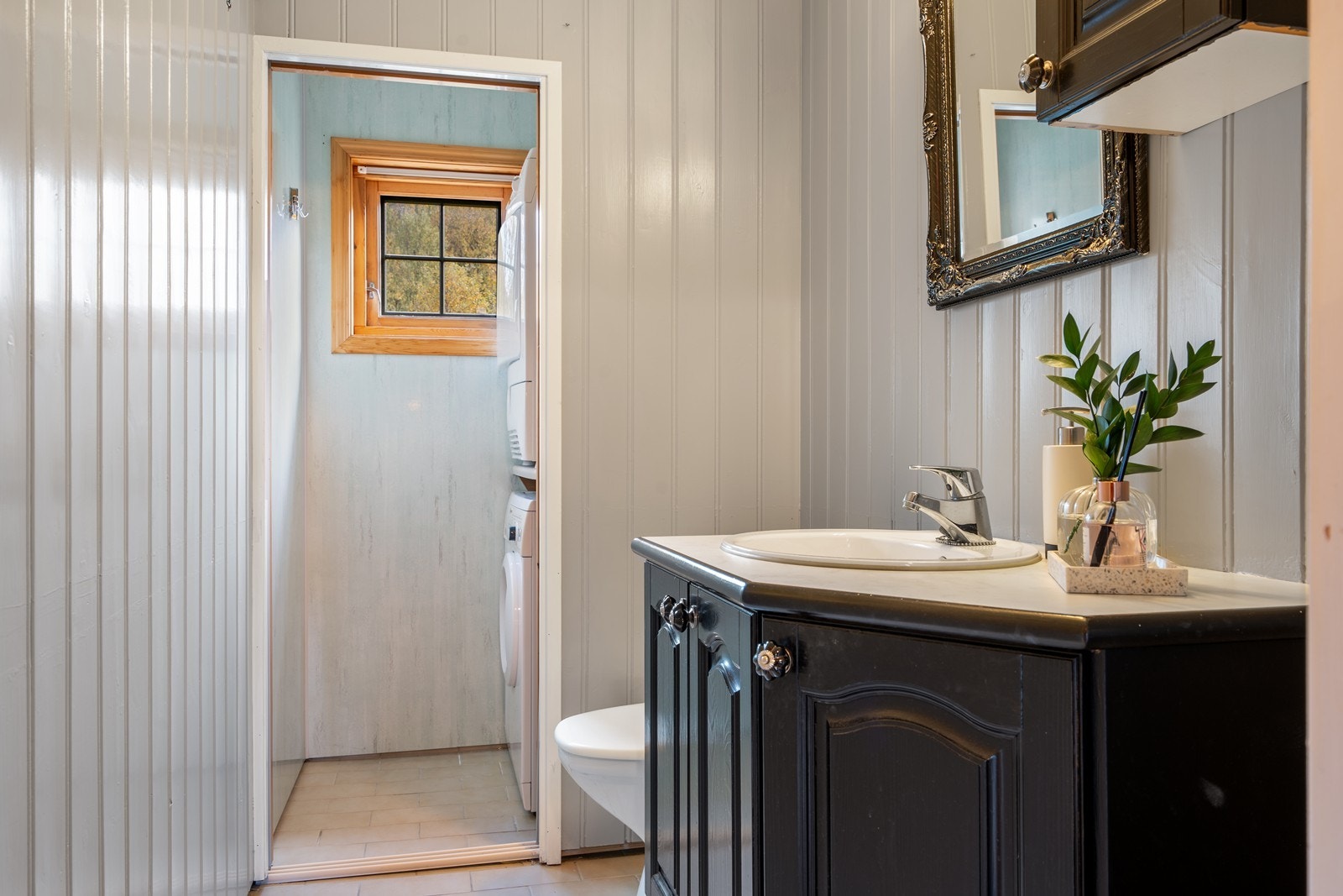 Hytten har også et WC/vaskerom som inneholder innredning med nedfelt servant, toalett og opplegg for vaskemaskin. Det er montert elektrisk styrt vifte. Veggene har panel og baderomsplater. Taket har baderomsplater. Gulvet er flislagt og har varmekabel. Galleribilde