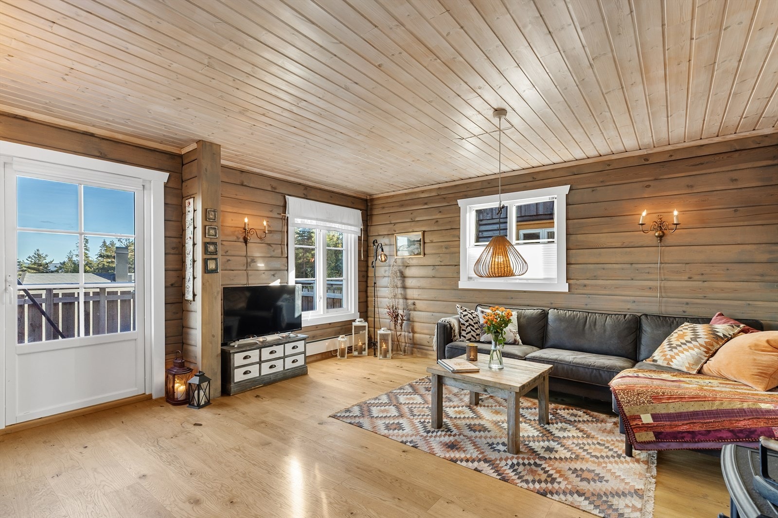 Fyr opp i peisen og slapp av i den koselige stua med beisede tømmervegger og lysnet takpanel. Galleribilde