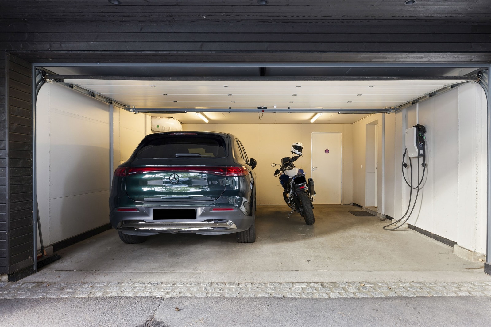 Parkering i integrert garasje med elektrisk port samt elbillader. Biloppstillingsplasser i gårdsplass med varmekabler. Galleribilde