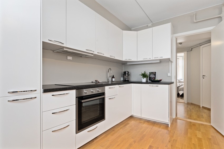 Stilrent kjøkken med hvite, slette fronter og integrerte hvitevarer. Galleribilde