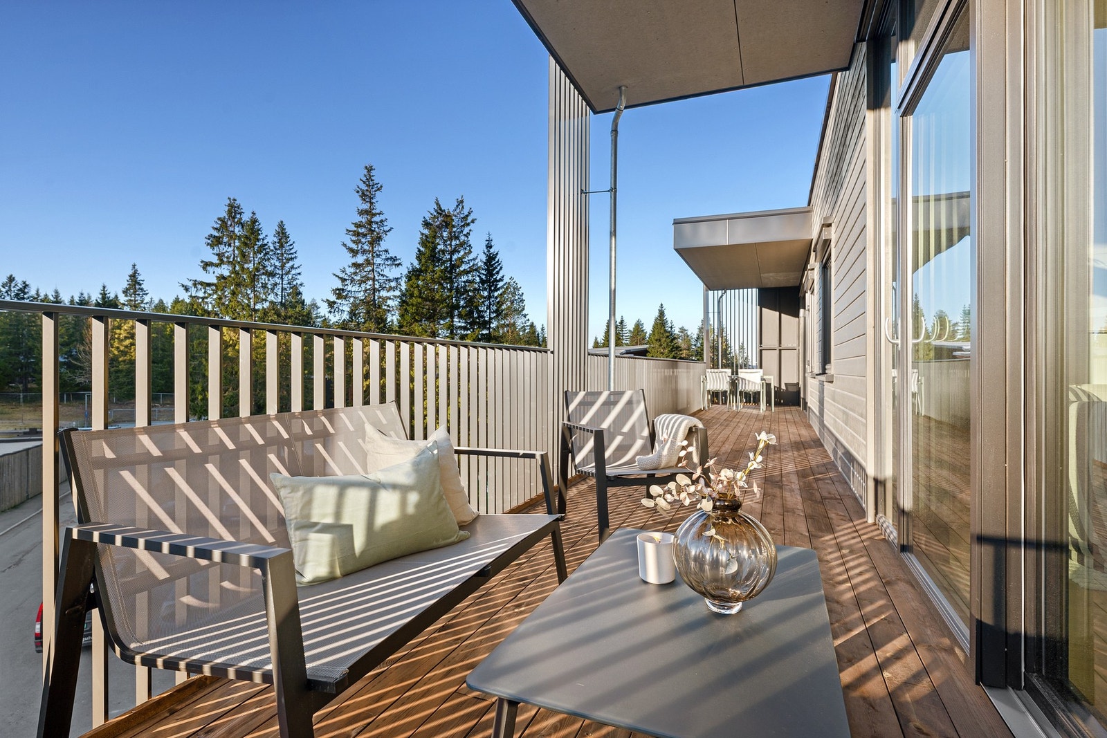 Stor og svært solrik balkong med tredekke, perfekt som en naturlig forlengelse av oppholdsrommene. Store skyvedører fra både stue og kjøkken gir en sømløs overgang mellom inne og ute. Galleribilde