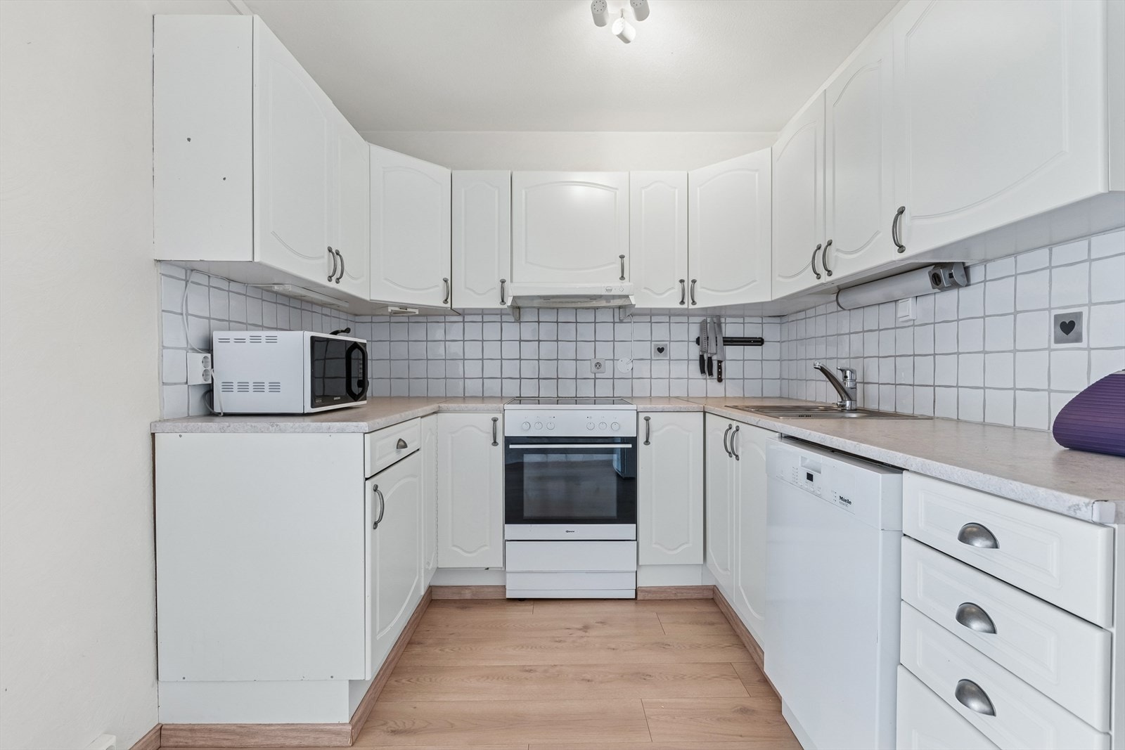 Det er dobbel stålvask og fliser på vegg over benkeplaten. Galleribilde