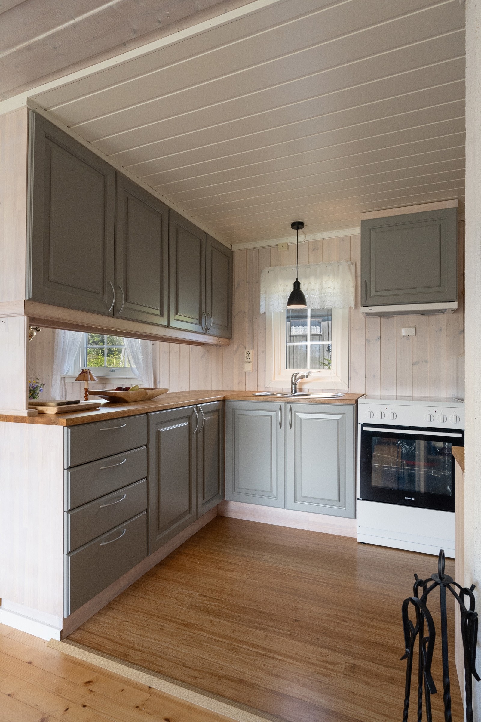 En halvøy fungerer som romdeler mot spisestua og gir ekstra oppbevaringsplass med overskap tilgjengelig fra kjøkkensiden Galleribilde