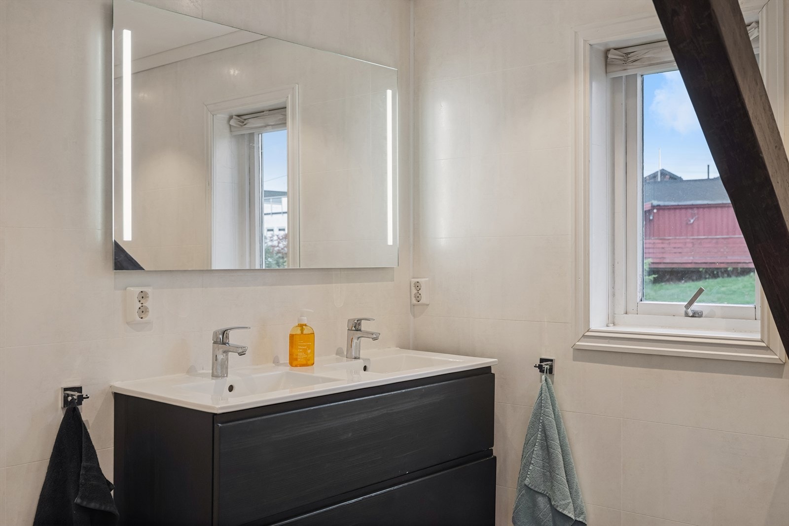 Badet fremstår med moderne løsninger og god plass. Her finner du en baderomsinnredning med to nedfelte servanter og tilhørende skap, samt et høyskap montert på vegg for praktisk oppbevaring. Galleribilde