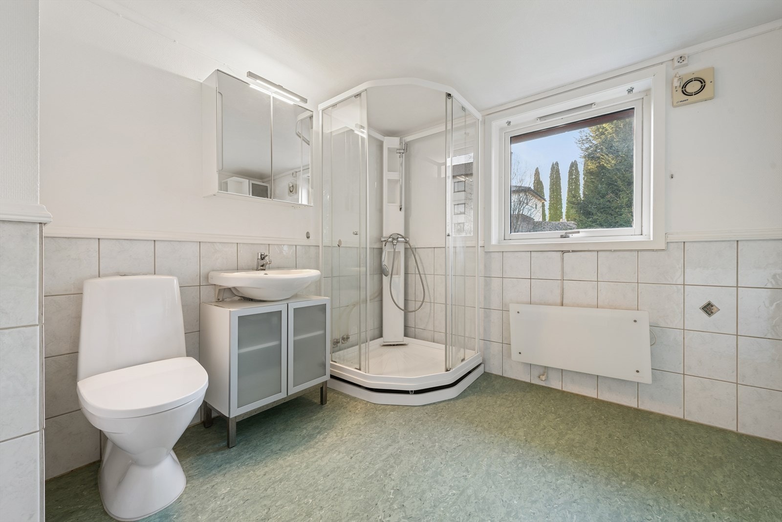 Badet er av eldre dato, med delvis flislagte vegger, slette overflater i himlingen og vinylbelegg på gulvet. Galleribilde