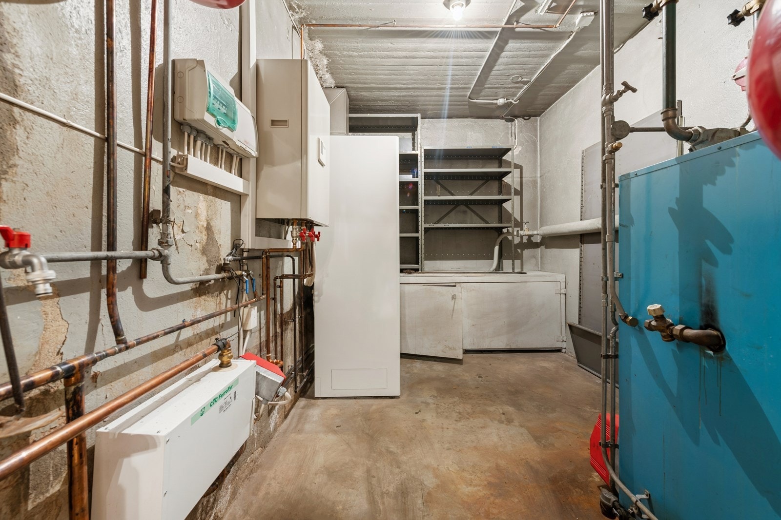 Teknisk rom med synlige kobberrør og automatsikringer gir enkel tilgang til boligens tekniske installasjoner. Betonggulv og ubehandlet vegg sikrer et robust rom for vedlikehold. Galleribilde
