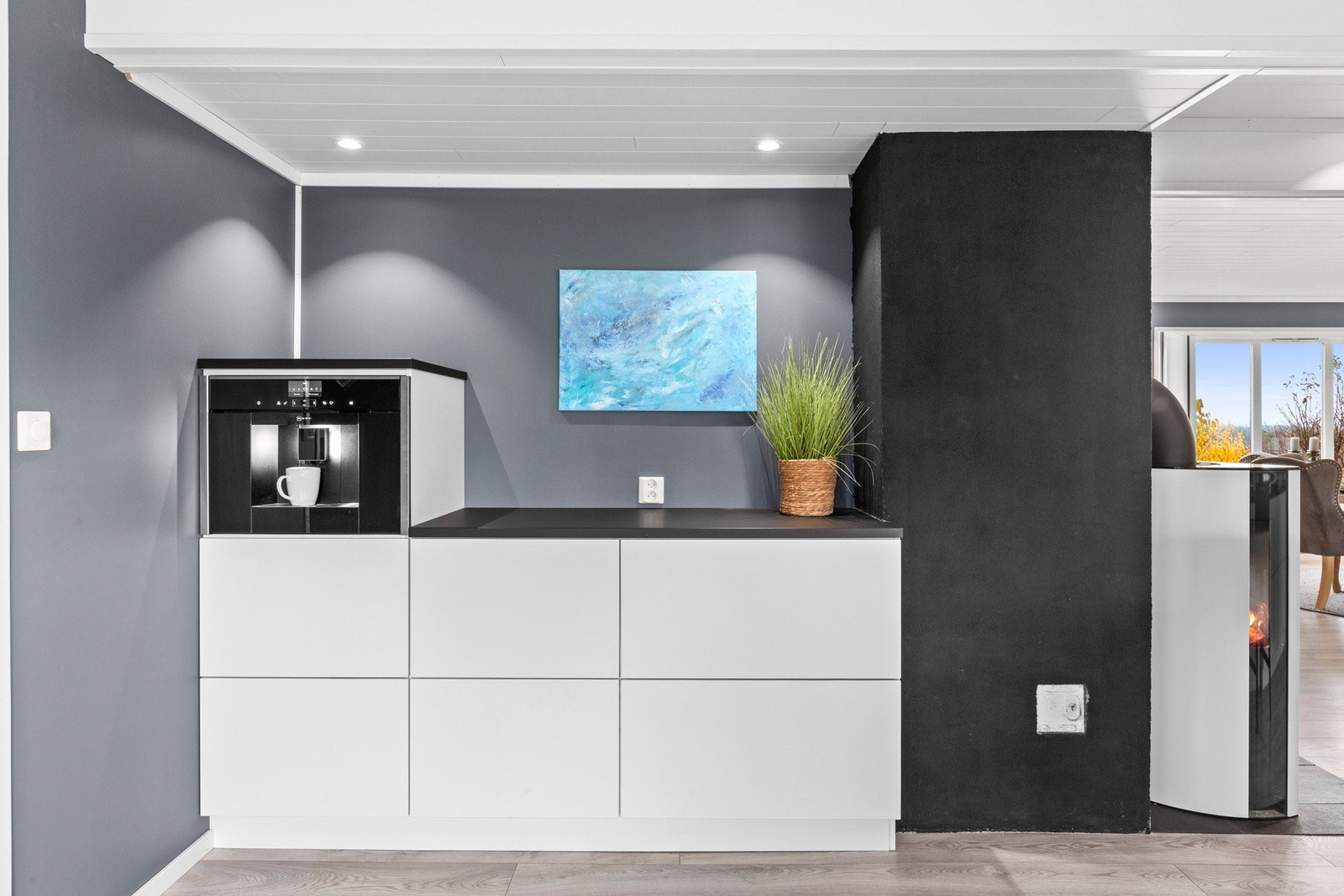 Arbeidsflatene består av laminat benkeplater, både på den lange kjøkkenøya og på innredningen bak peisen der kaffemaskinen er installert. Galleribilde