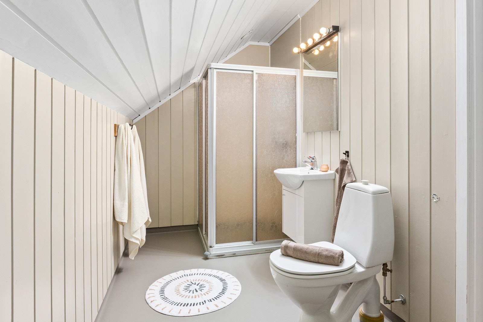 Badet har dusjhjørne, gulvstående wc, servant og speil. Galleribilde