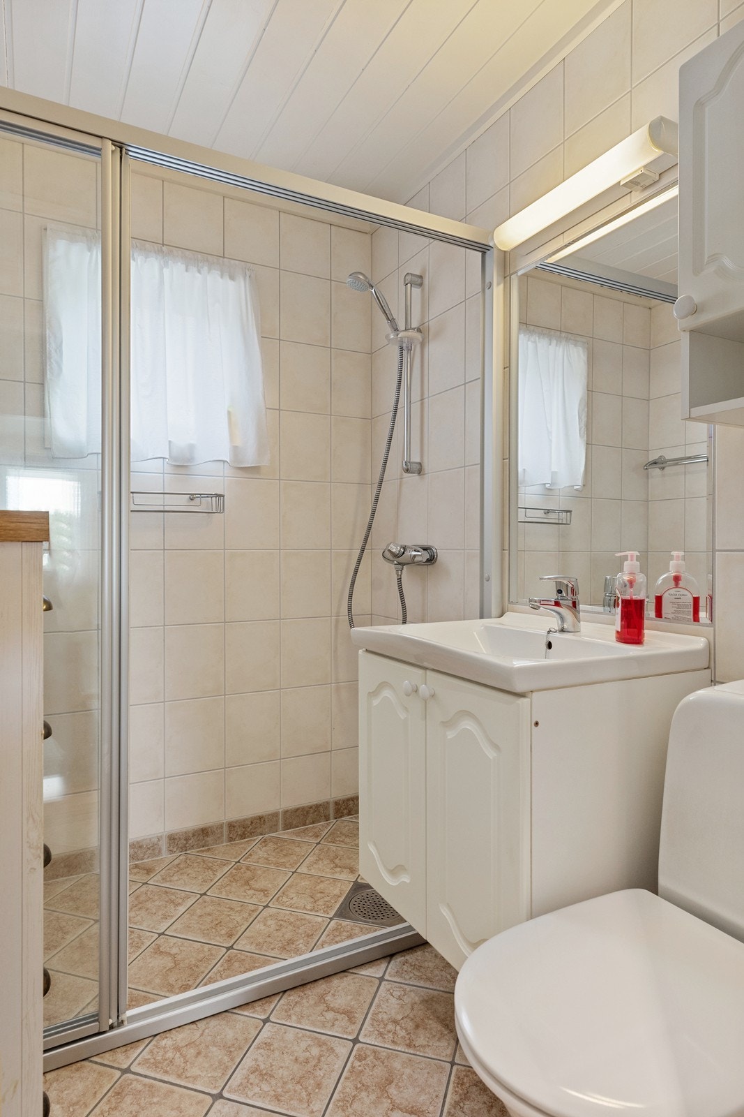 Badet har innredning med nedfelt servant, gulvfestet toalett og dusjvegger. Galleribilde