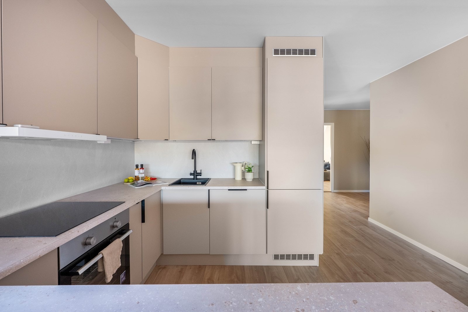 Kjøkkeninnredning fra HTH med glatte fronter og benkeplate av laminat. Det er integrerte hvitevarer som platetopp, komfyr, kjøl/frys og oppvaskmaskin. Galleribilde