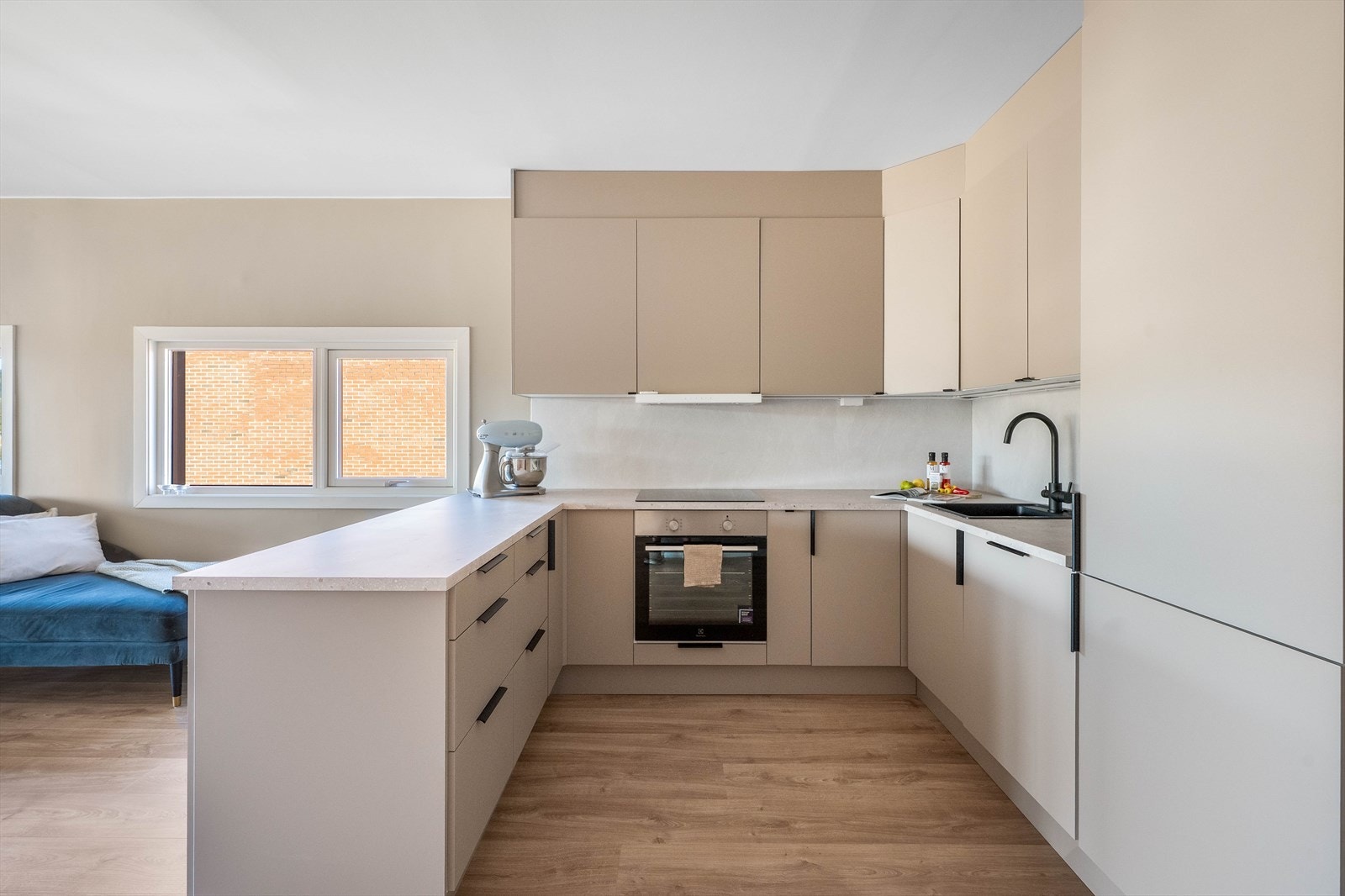 Lyst, innholdsrikt og pent kjøkken fra 2025, i åpen løsning med stuen. Galleribilde