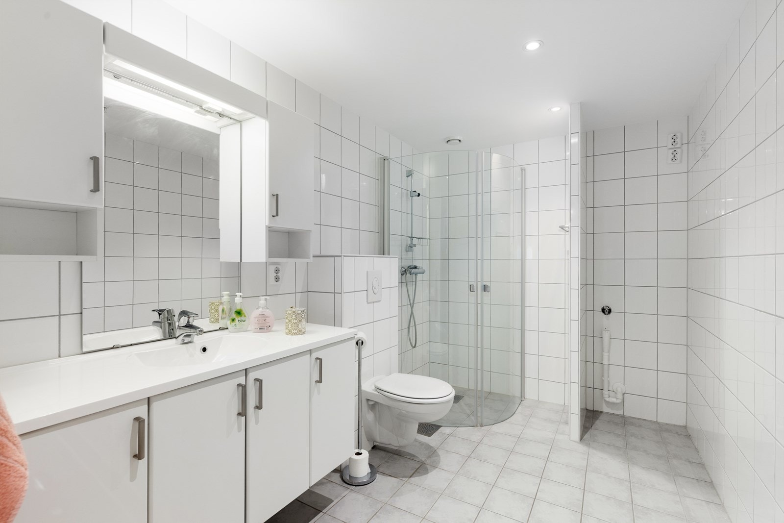 Badet har også dusjhjørne med glassvegger, veggmontert toalett og egen sone med opplegg for og plass til vaskemaskin. Galleribilde