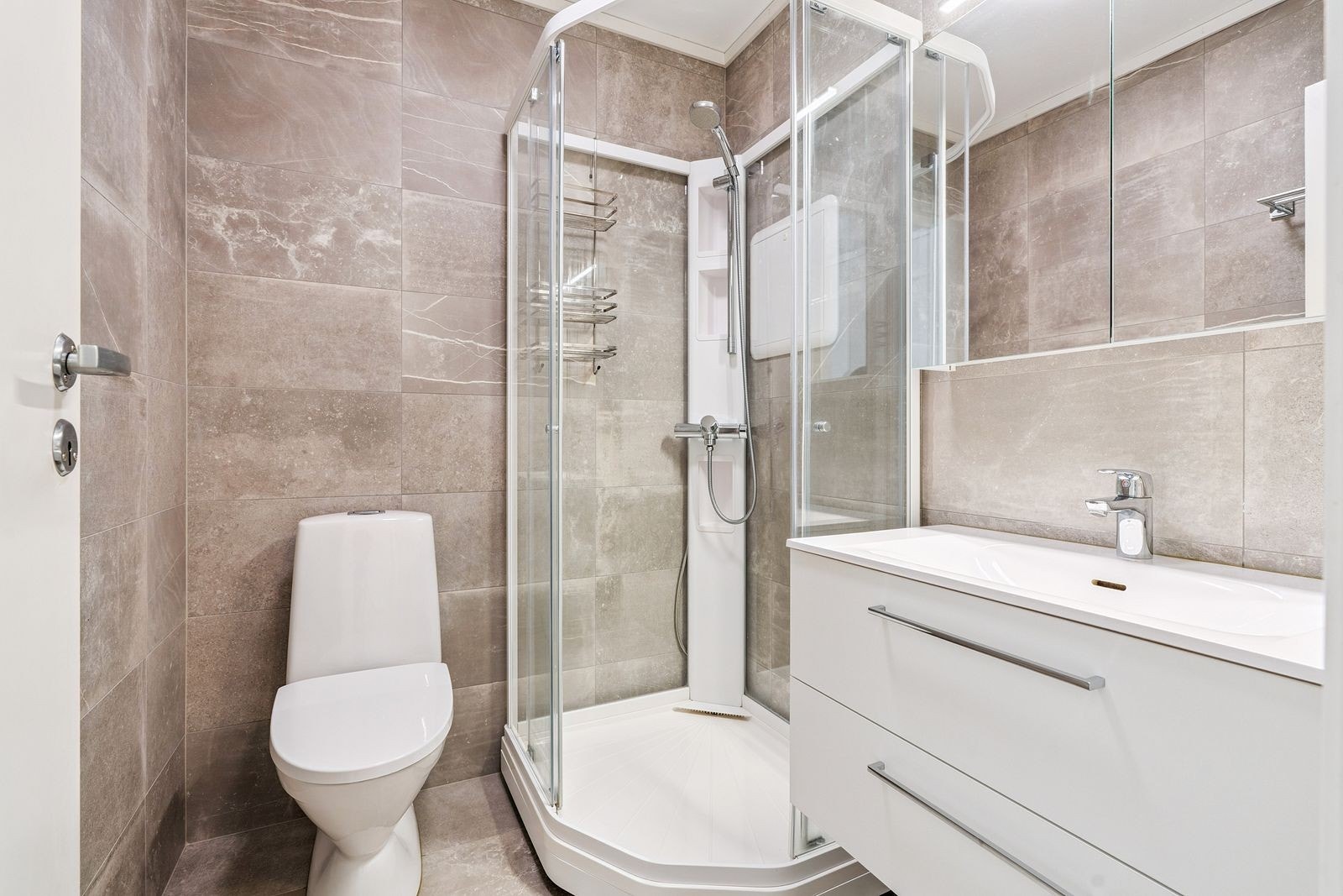 Flott flislagt bad med varme i gulv. Badet har dusjkabinett, toalett og servant med underskuffer. Galleribilde