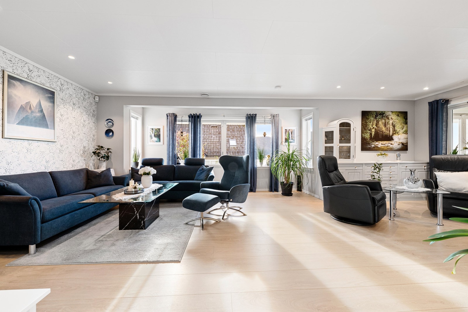 Stor og innbydende stue med laminatgulv og innfelte spotter i tak Galleribilde