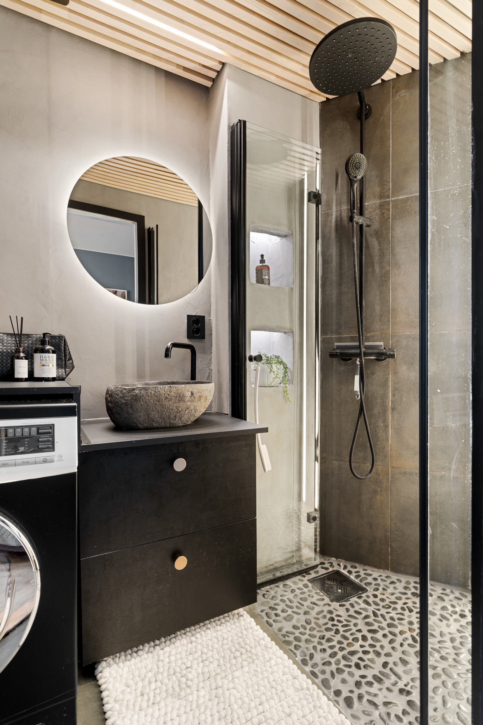 Innredningen består av overliggende servantskål, skuffeseksjoner til oppbevaring og speil med integrert lys. Badet har også opplegg for vaskemaskin, regnfallsdusj og stilrene spiler i tak. Galleribilde