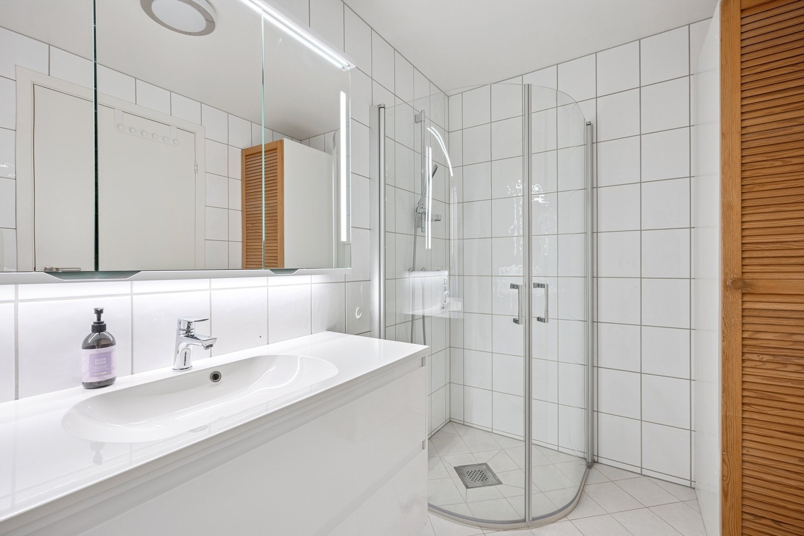 Pent bad med fliser på gulv og vegger. Badet er innredet med baderomsinnredning, toalett og dusjløsning. Galleribilde