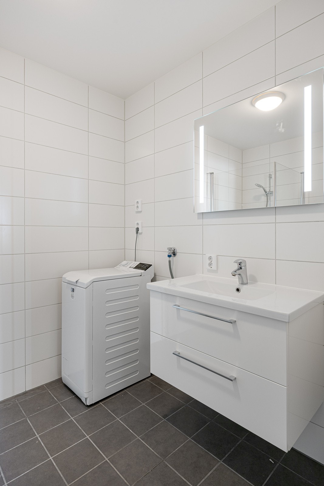 Leiligheten har et moderne og pent bad med hvite fliser på veggene og grå fliser på gulv med elektrisk gulvvarme. Galleribilde