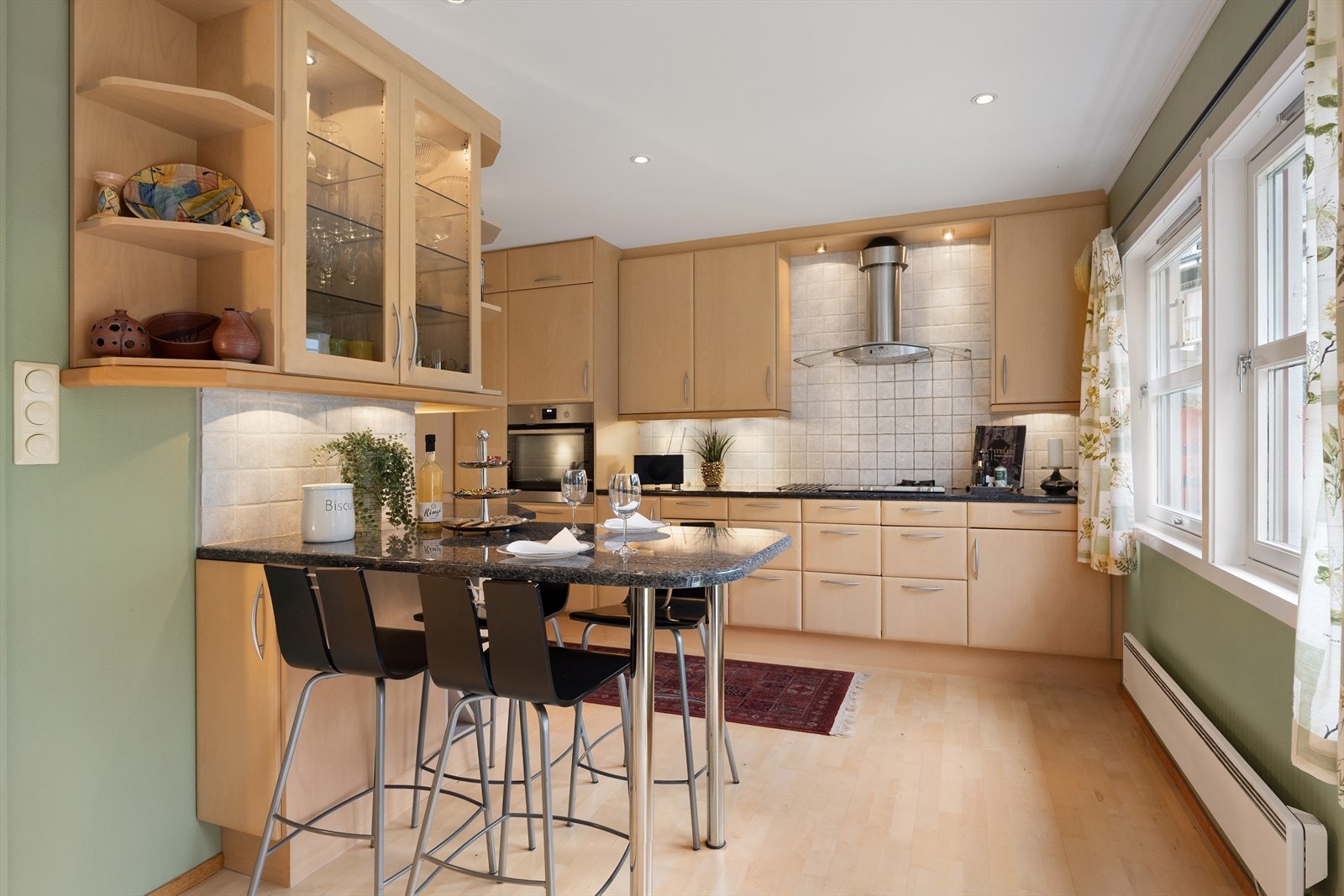 Kjøkkenet er lyst og pent med store vindusflater og fint utsyn mot hagen Galleribilde