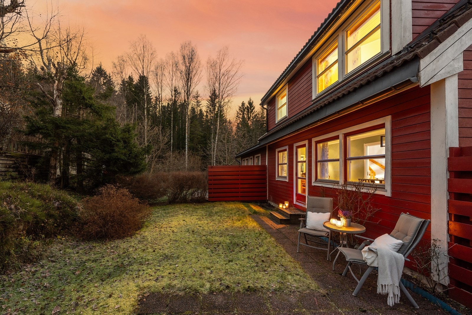 Uteplass med heller, samt fin gressplen, beplantning og noe naturtomt Galleribilde