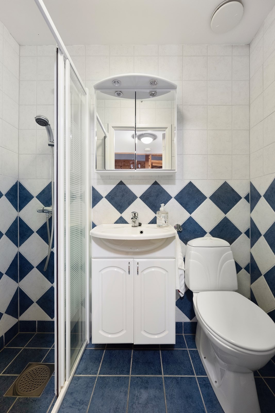 Pent bad med flislagte vegger og gulv. Badet er innredet med servant med underskap, speil med belysning og toalett. Varmekabler i gulv Galleribilde