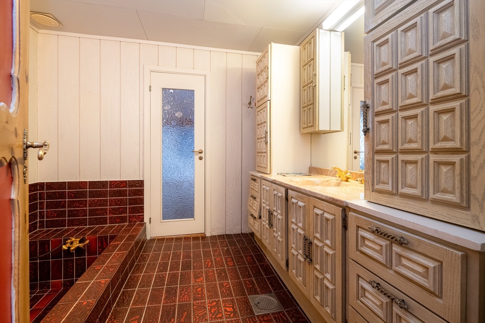 Eldre bad med flis på gulv og flis/panel på vegger. Galleribilde