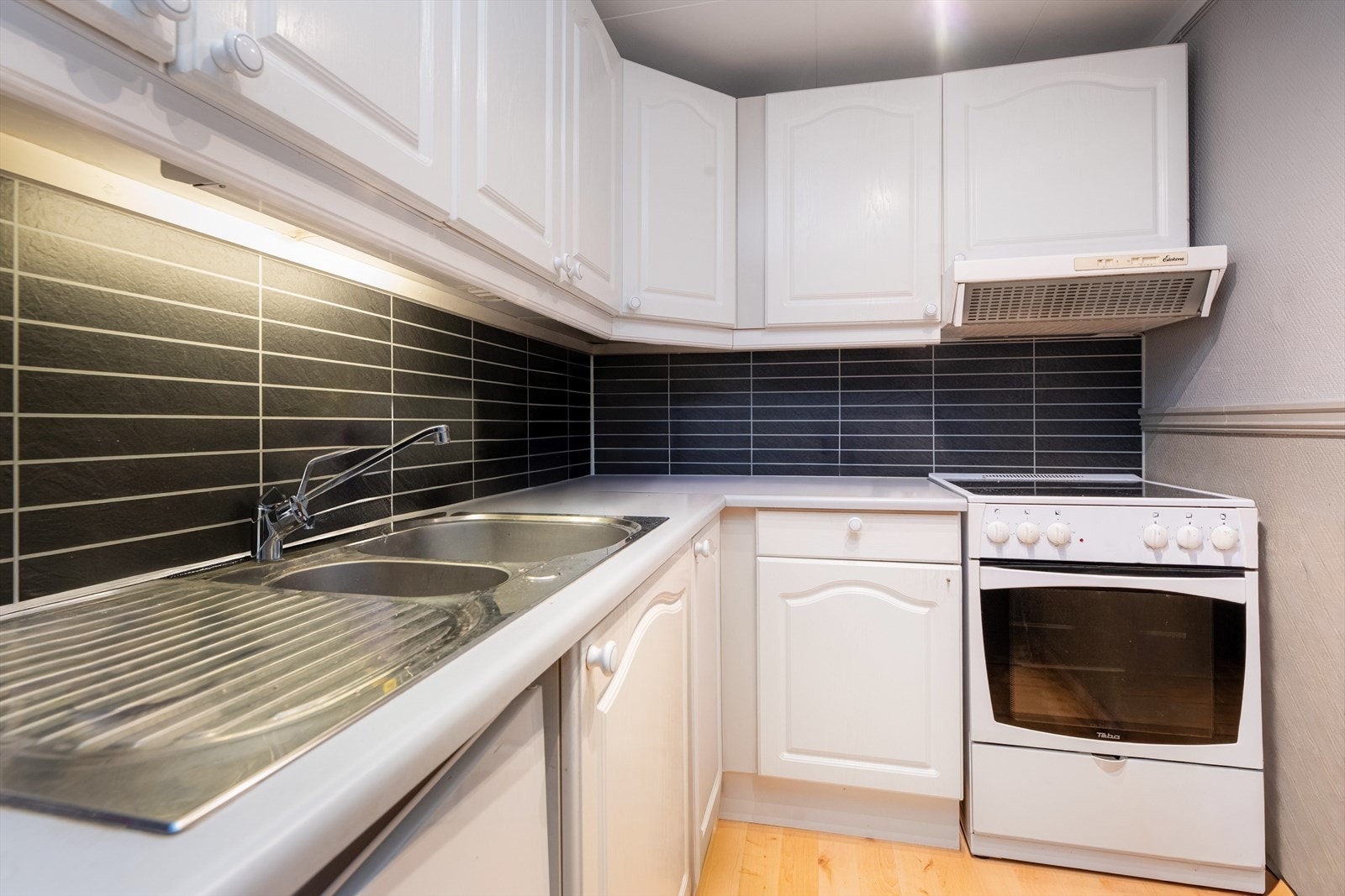 Kjøkkenet har innredning med glatte fronter og benkeplate av laminat. Over stekesone er det ventilator med kullfilter. Galleribilde