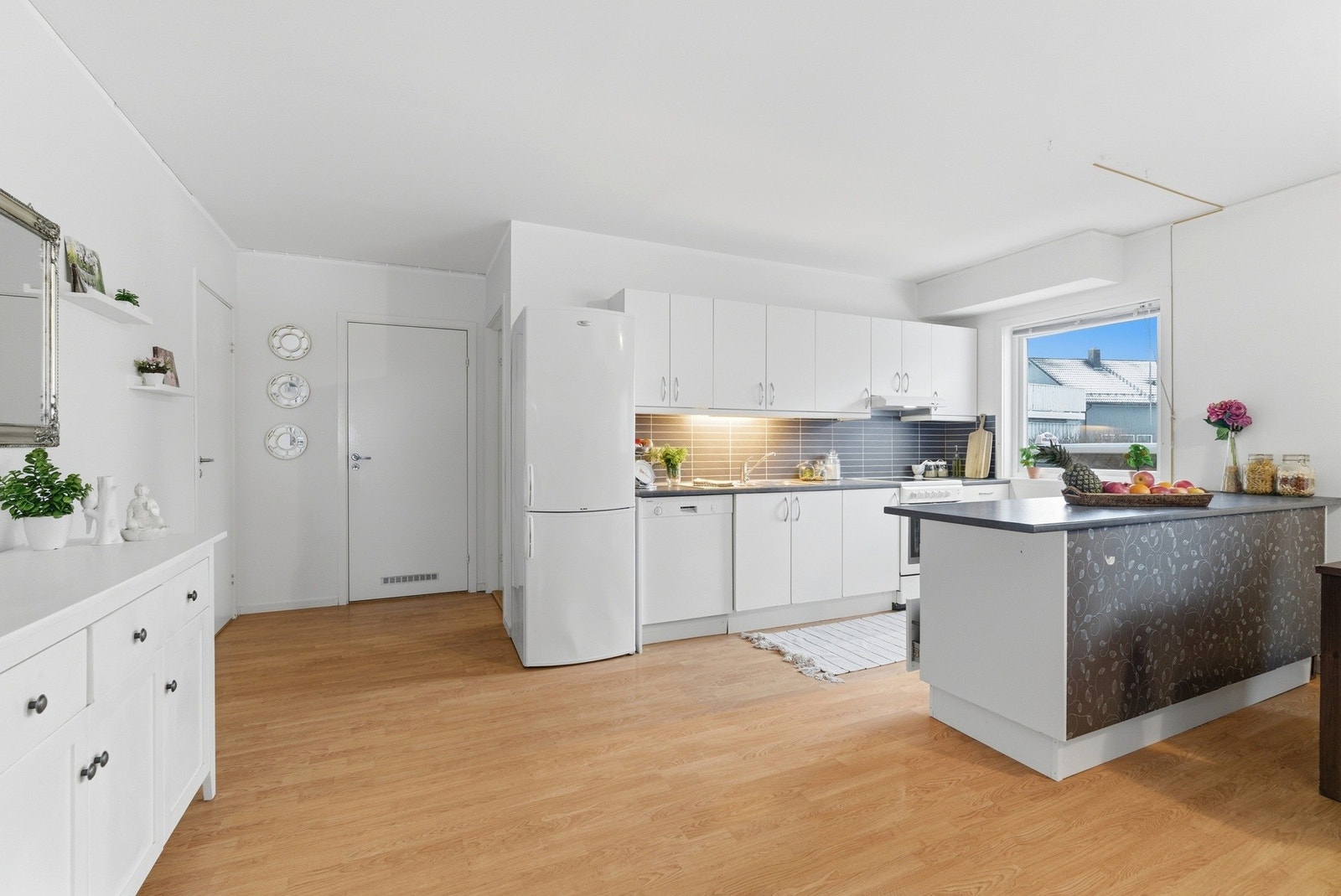 Lyst og stilrent kjøkken med praktisk kjøkkenhalvøy, som skaper et naturlig skille mot stuen. Galleribilde