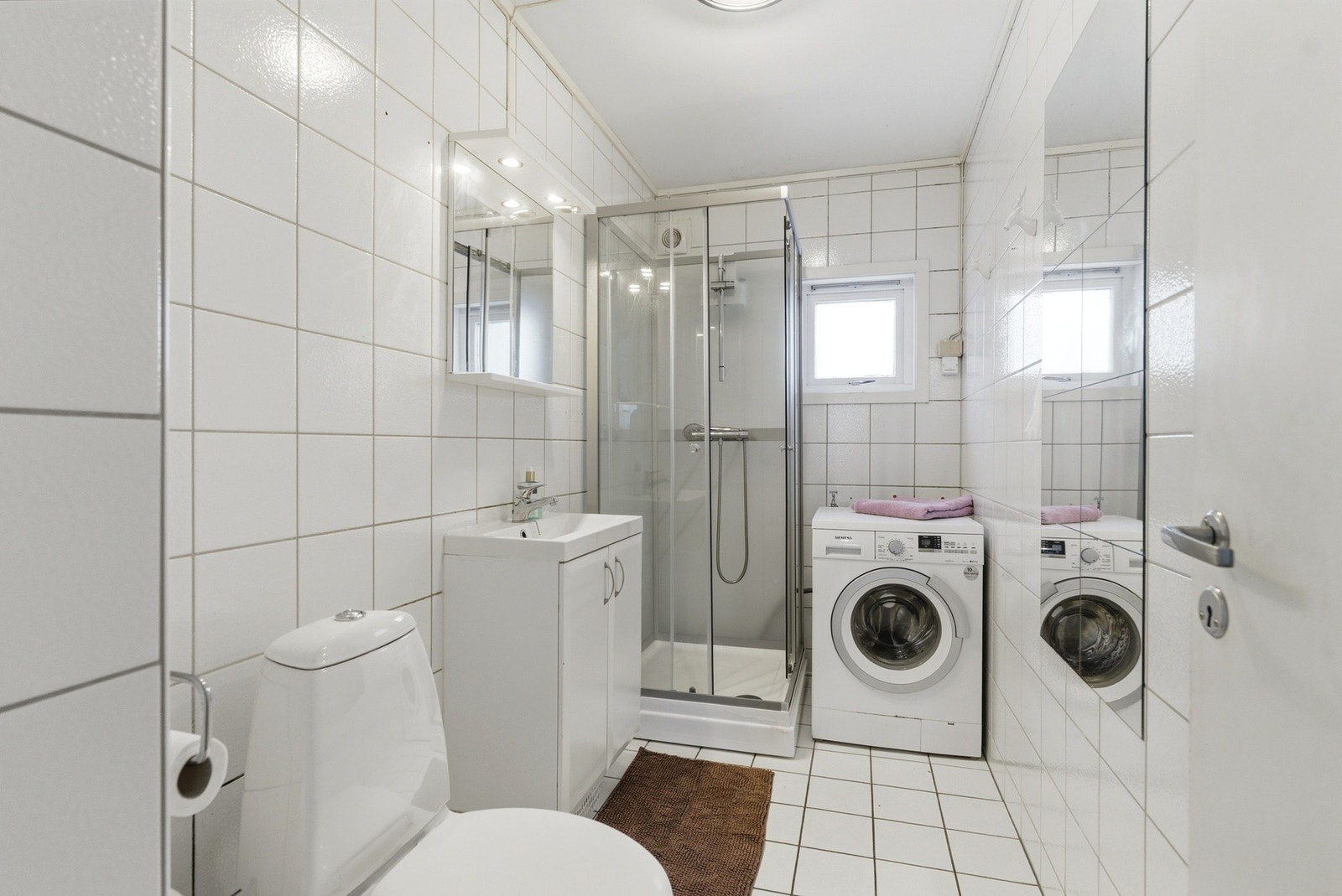 Flislagt bad med varmekabler i gulvet. Rommet har lys innredning, toalett og dusjkabinett. Det er opplegg for vaskemaskin. Galleribilde