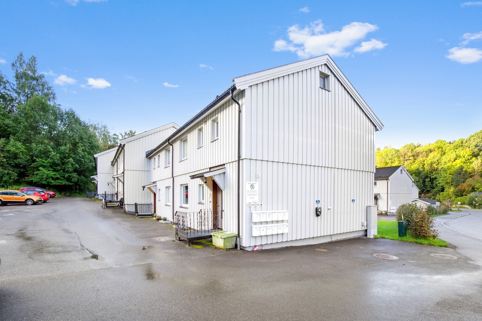 Leiligheten ligger i første rekke, med parkering rett utenfor døren og gjesteparkering langs sideveggen. Galleribilde