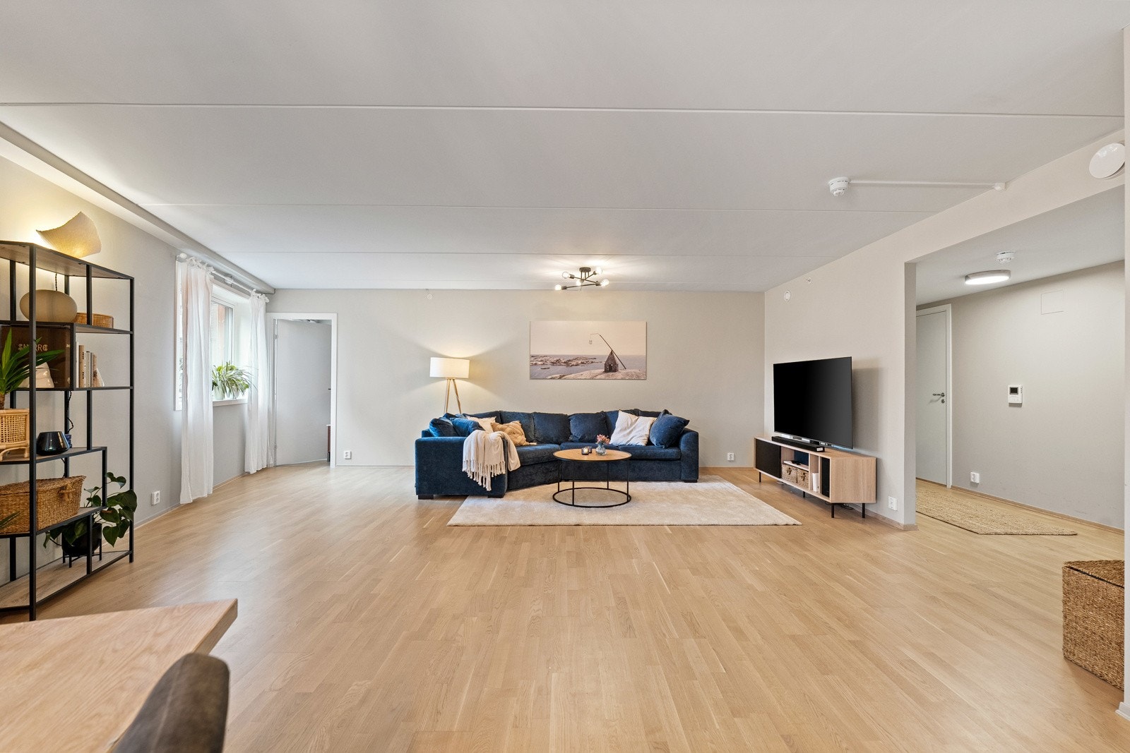 Romslig stue med lyse overflater og parkett på gulv. Galleribilde