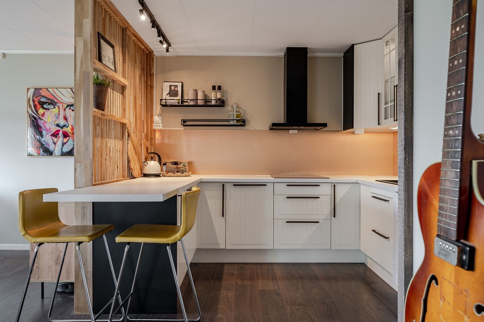 Kjøkkeninnredning fra 2023, deler med gjenbrukt komponenter. Innredningen har lyse fronter og laminert benkeplate med nedfelt oppvaskkum. Praktisk med plater i benkeryggen og belysning under de takhøye overskapene. Galleribilde