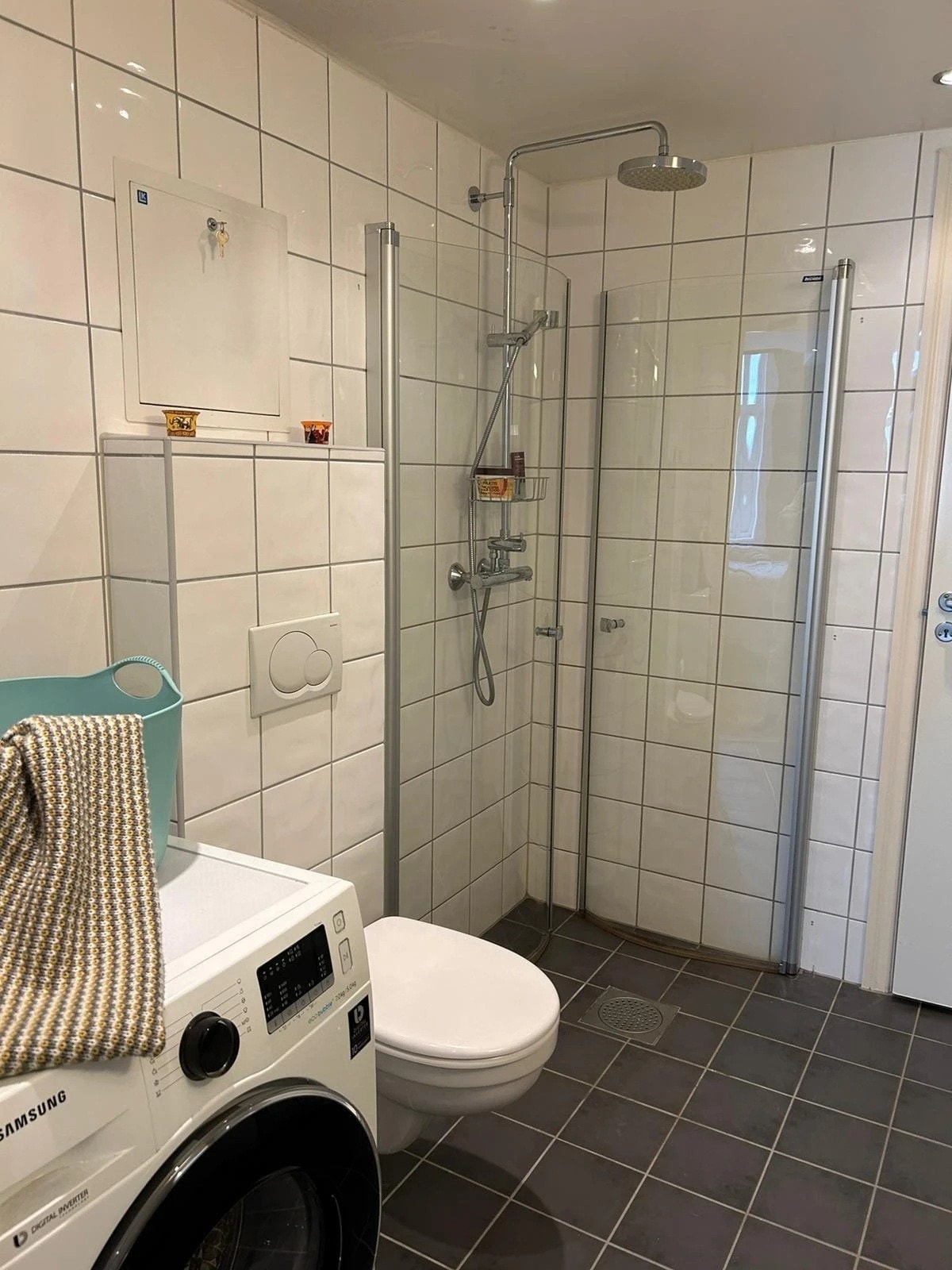 Helfliset badrom utstyrt med dusj, wc og kombinert vaskemaskin og tørketrommel. Galleribilde