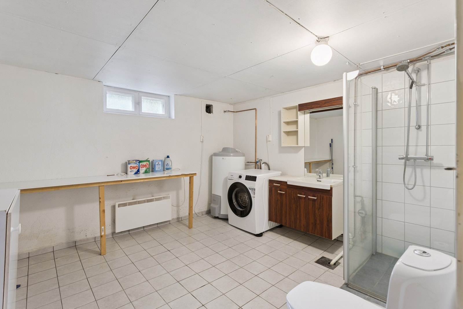 Praktisk vaskerom i kjeller, med flislagt gulv, dusjnisje, toalett og opplegg for vaskemaskin. Galleribilde