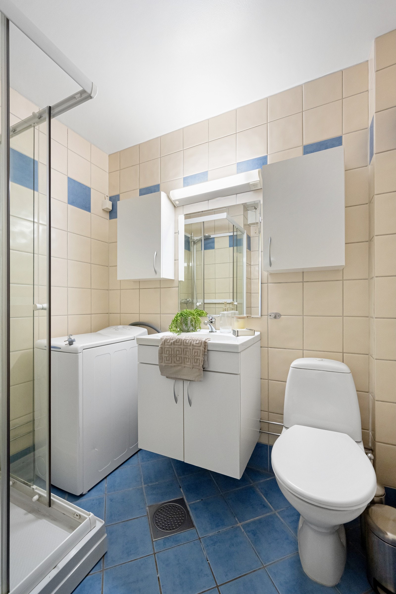 Badet er utstyrt med servant i innredning, overskap med speil og belysning, dusjkabinett, toalett og opplegg for vaskemaskin Galleribilde